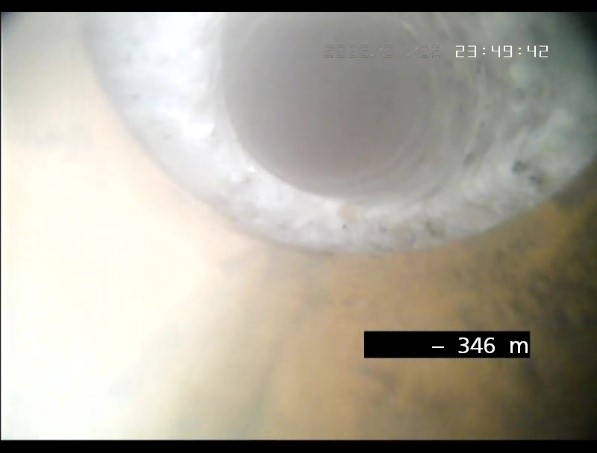 Mit einer Kamera prüft das Bohrteam den Zustand des Bohrpfades. Das Bild zeigt den Ausgang der rotbraunen Ablenkvorrichtung und den Ansatz der Ablenkbohrung in den weißmarmorierten Granit bei einer Bohrung in 346 Meter Tiefe. 